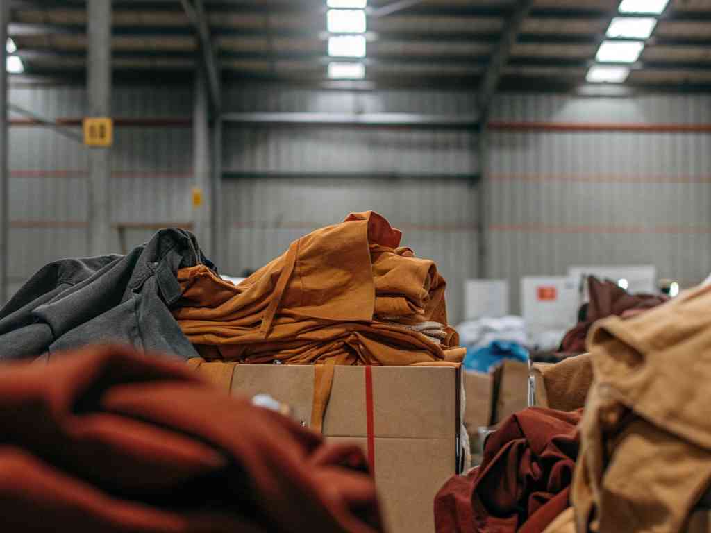 Colorful fabric piles in warehouse setting.
