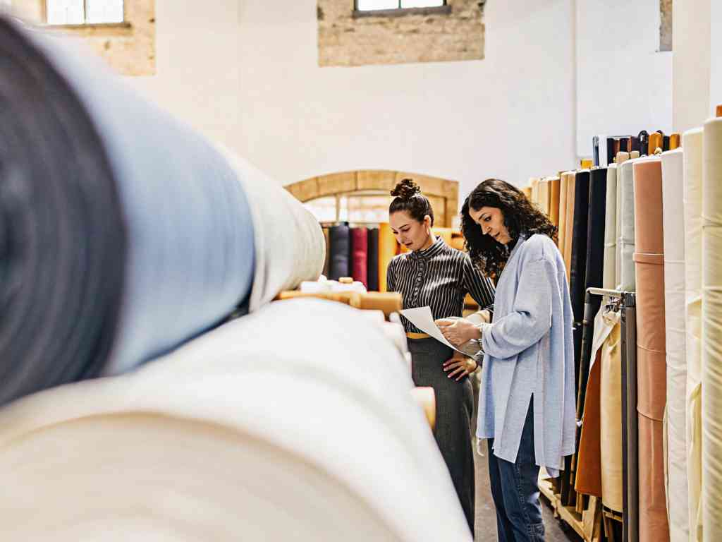 Two women examining documents in a fabric store.