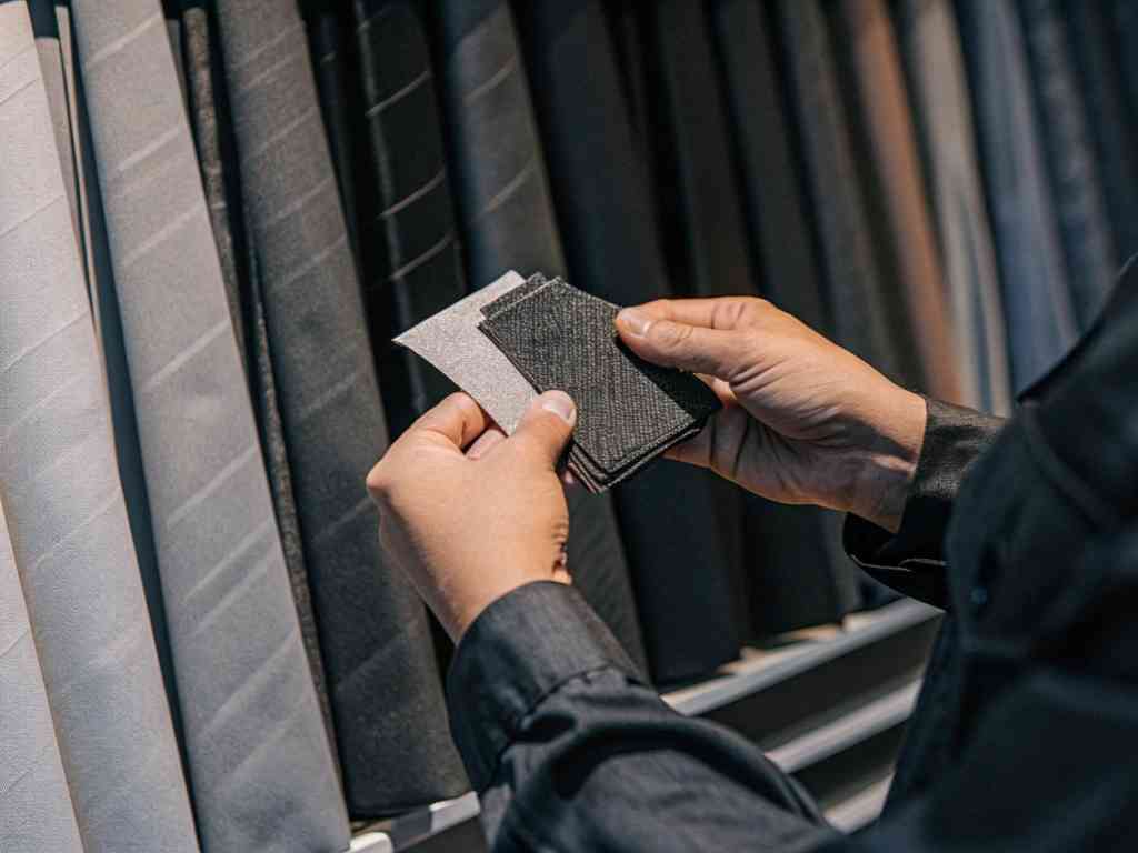 Person comparing dark fabric swatches in store.