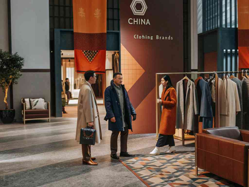 People discussing at a clothing brand exhibition with coats on display.