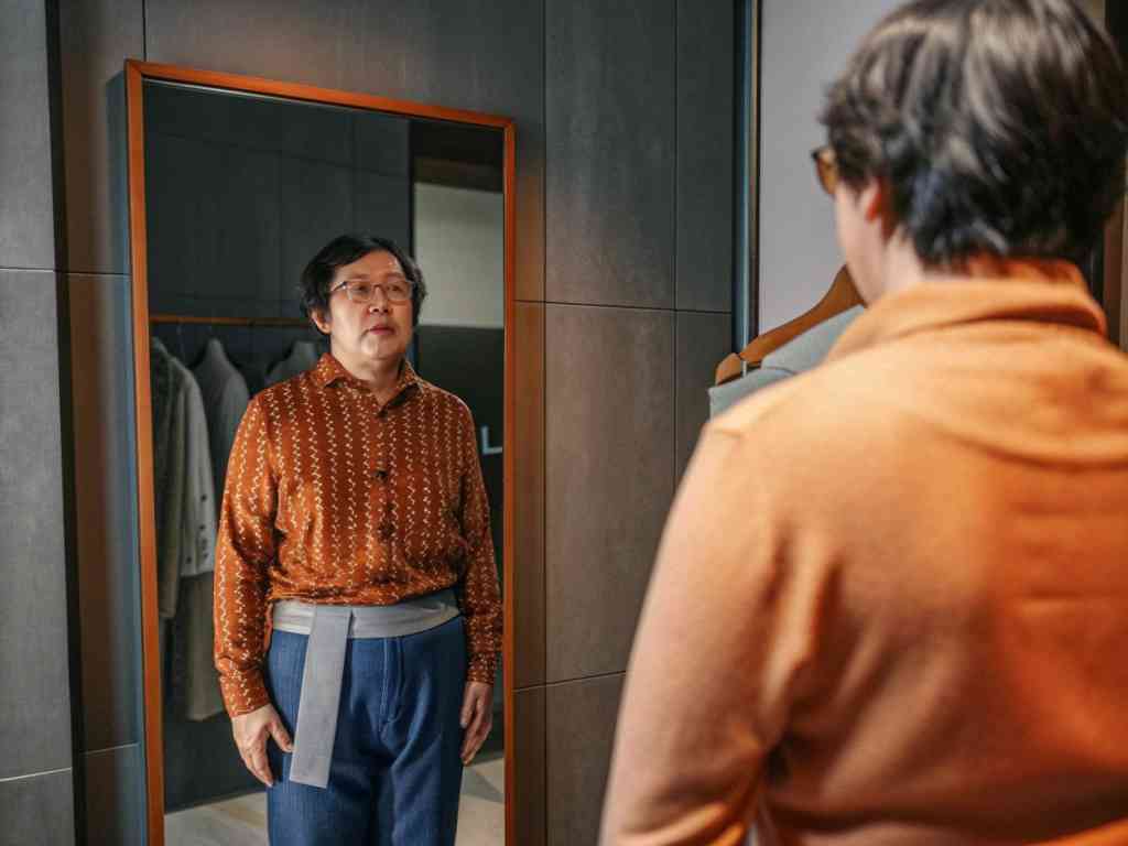 Person trying on outfit and looking in mirror.