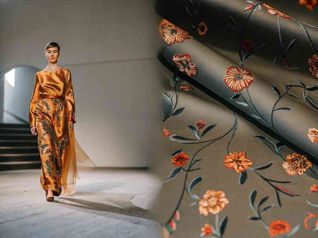 Woman in silk floral gown walking runway beside floral patterned fabric