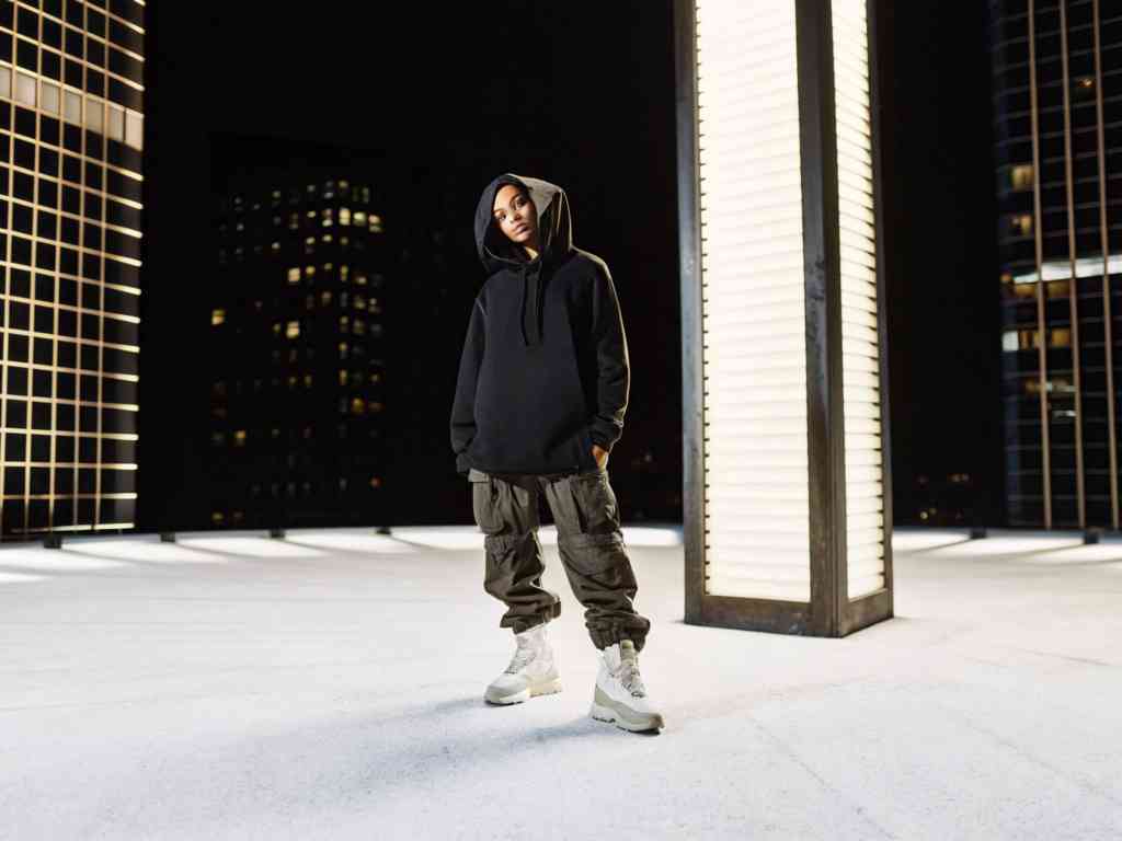 A stylish person in a black hoodie and cargo pants posing on a rooftop.