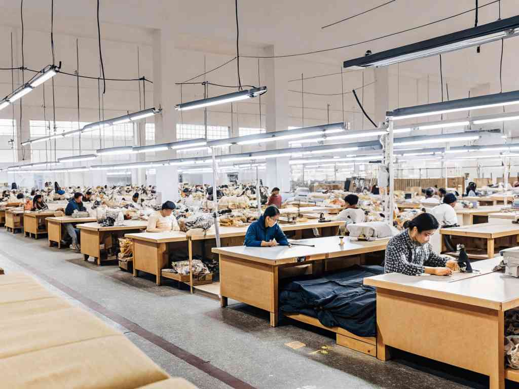 Workers in a large garment factory engaged in fabric cutting and sewing tasks.