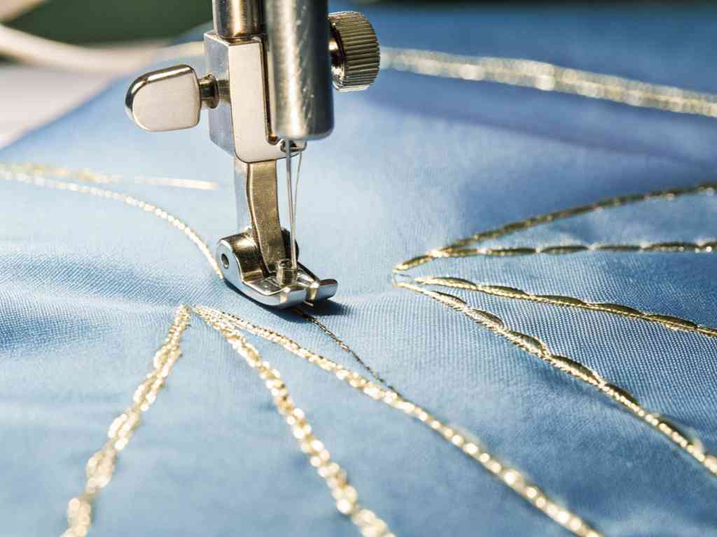 Sewing machine embroidering gold thread on blue fabric
