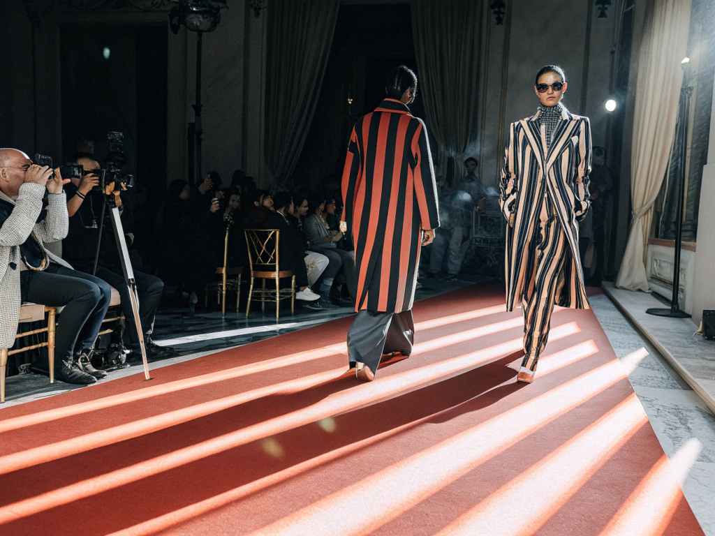 Models walking down the runway in bold striped outfits.