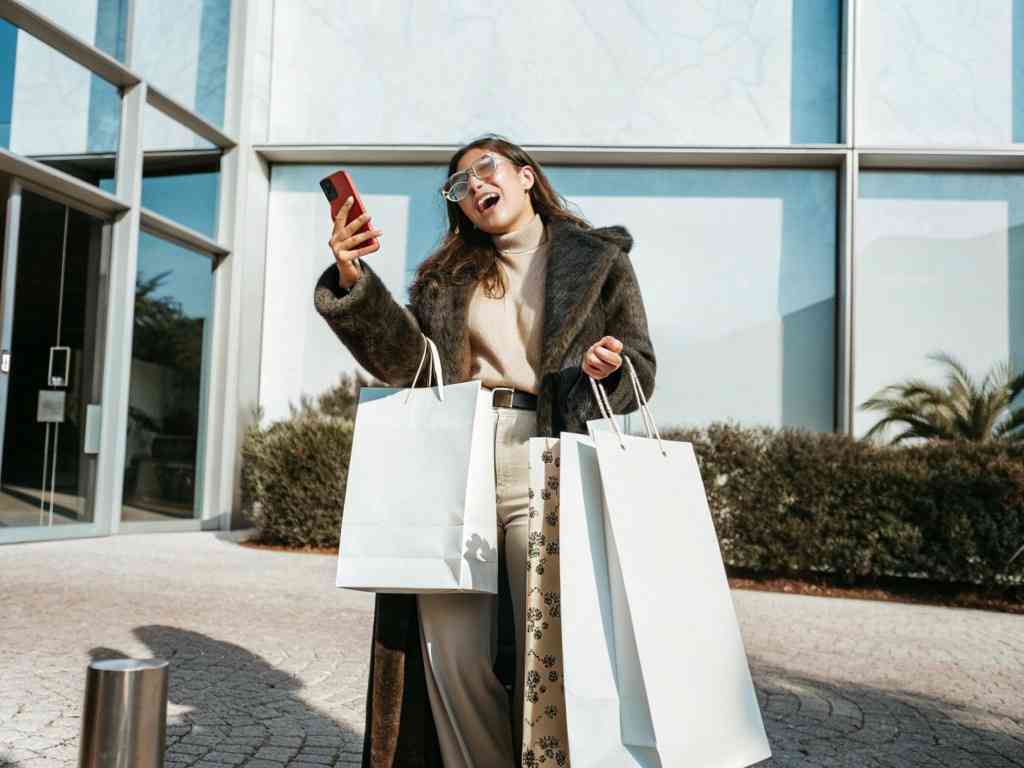 A stylish woman happily holding multiple shopping bags.