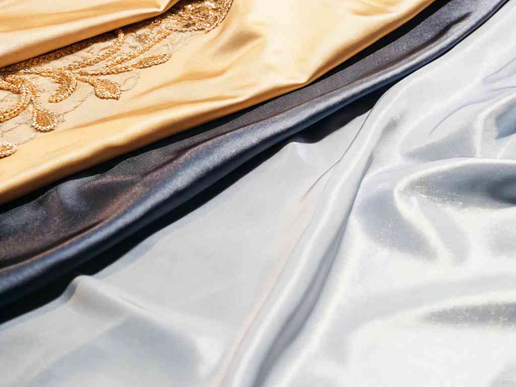 Soft satin fabrics in gold, navy, and silver with embroidery details.