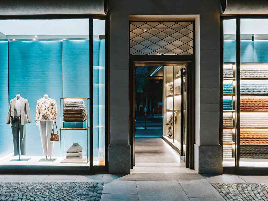 A stylish boutique with mannequins, folded sweaters, and illuminated displays.