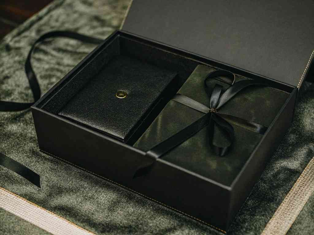 Elegant black gift box with a wallet and wrapped present.