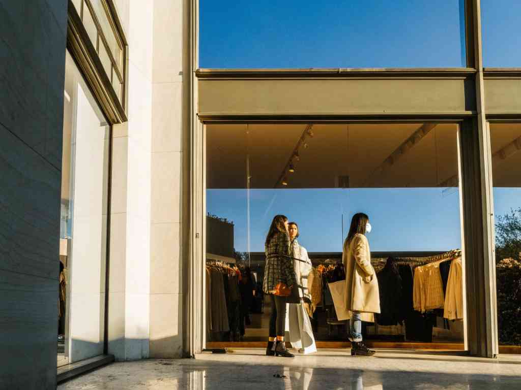 Shoppers standing outside a fashion boutique with large glass windows.