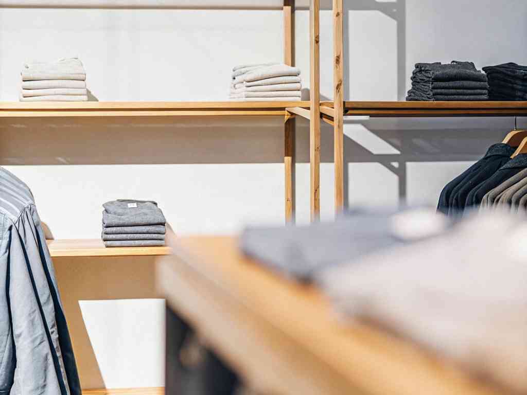 A neatly arranged clothing store with folded shirts and hanging garments.