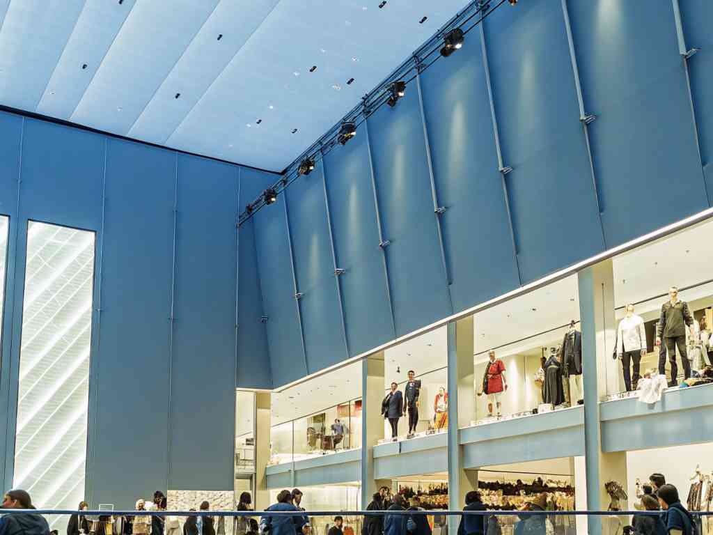 A spacious fashion store with mannequins and shoppers.