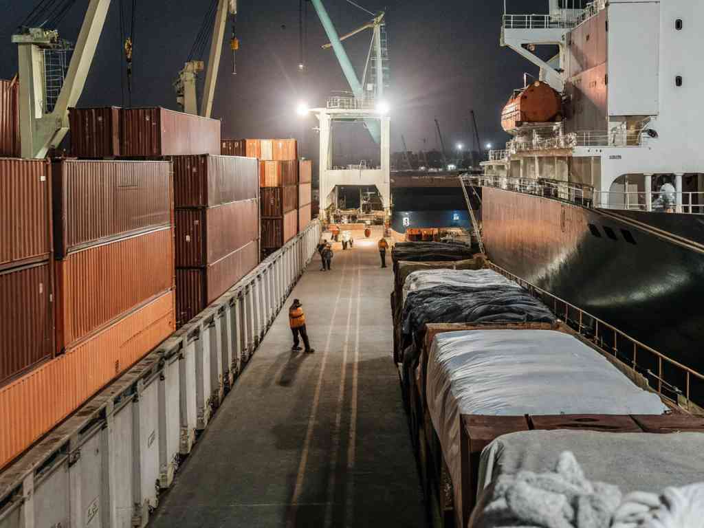 Shipping containers being loaded onto a cargo ship at night.