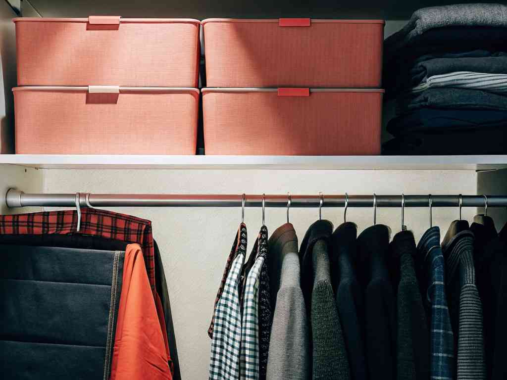 A neatly arranged closet with storage boxes and hanging clothes.