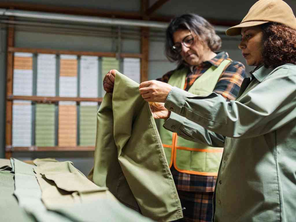 Two women inspecting olive green fabric.