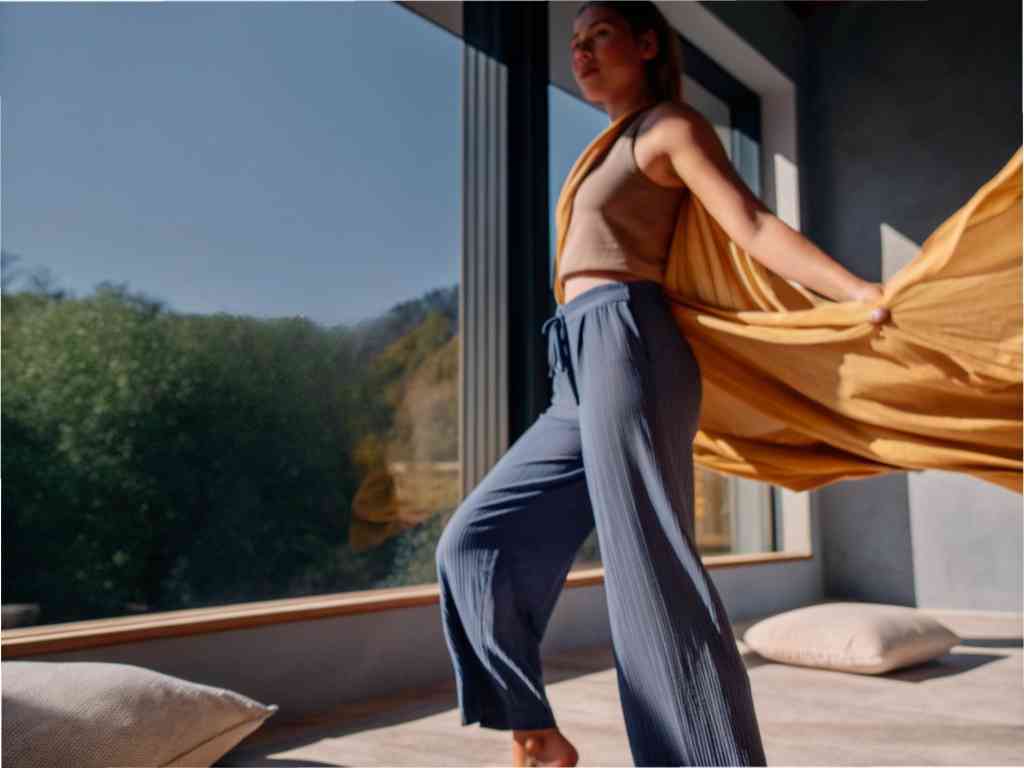 Woman posing indoors in flowy outfit.
