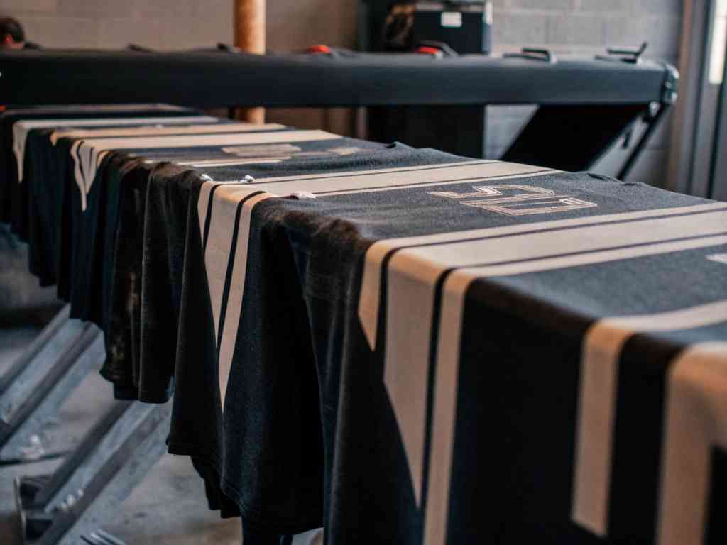 Black t-shirts laid out for screen printing in a professional studio.