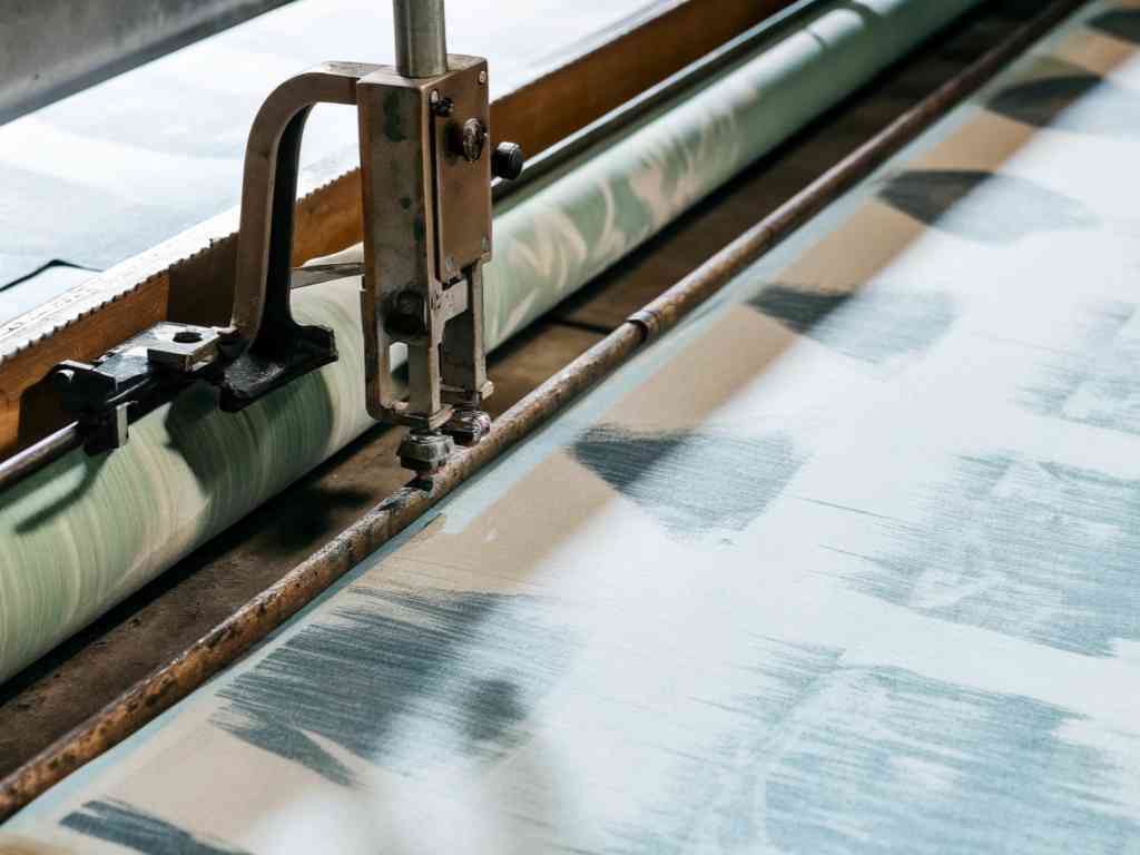 Industrial fabric cutter slicing patterned textile roll