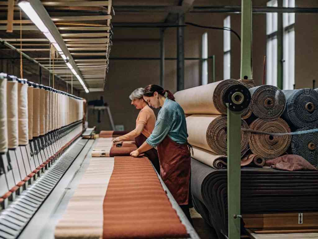 Two workers inspecting fabric rolls in a textile manufacturing facility.