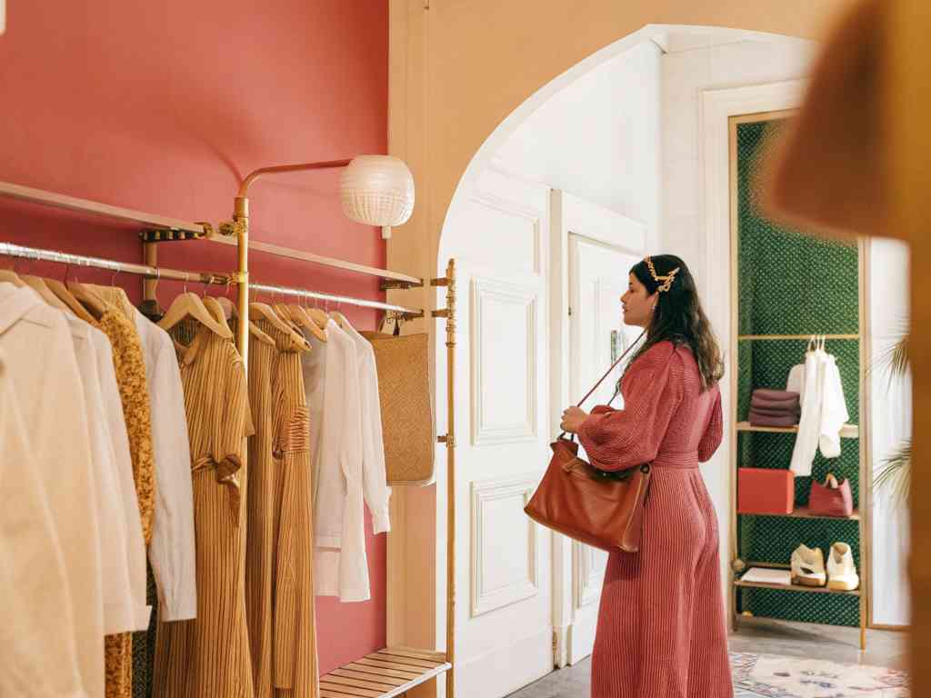 A woman in a red dress exploring a boutique with warm decor.