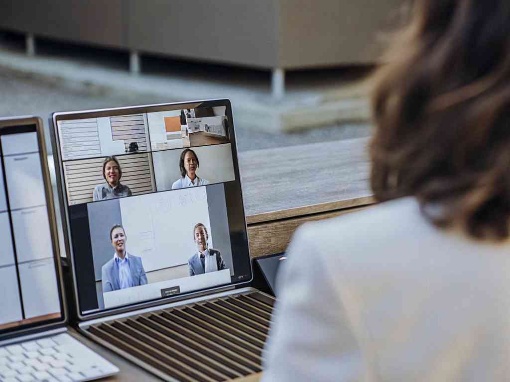 A woman attending a video conference with colleagues on her laptop.