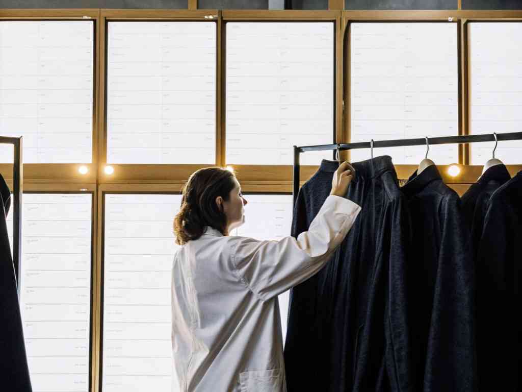 Woman inspects dark coats on rack in modern store