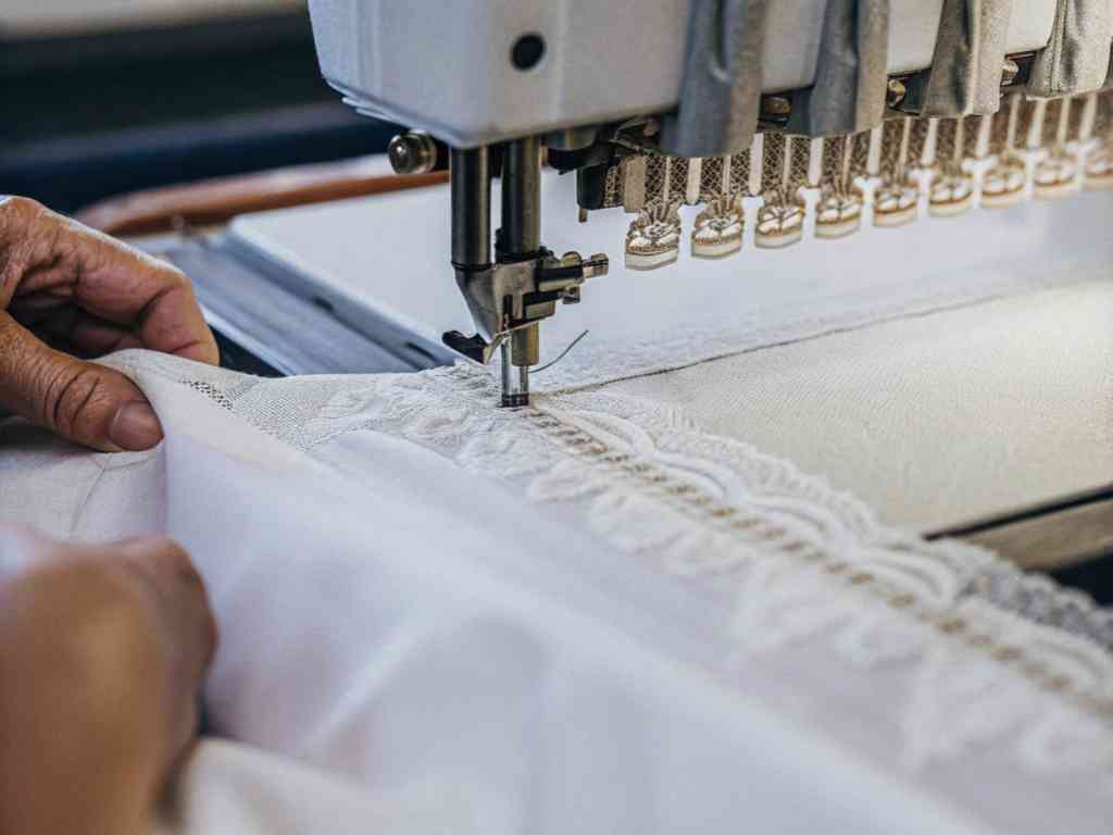 Hands guiding lace fabric through embroidery machine