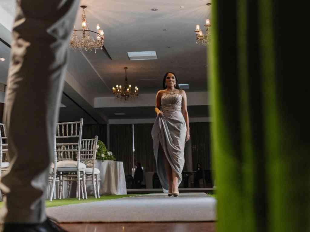 Model walking down runway in glamorous gown