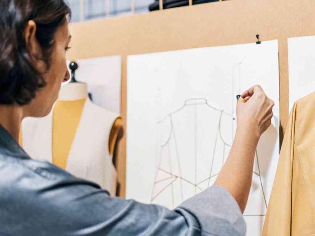 Designer sketching fashion pattern on wall-mounted paper