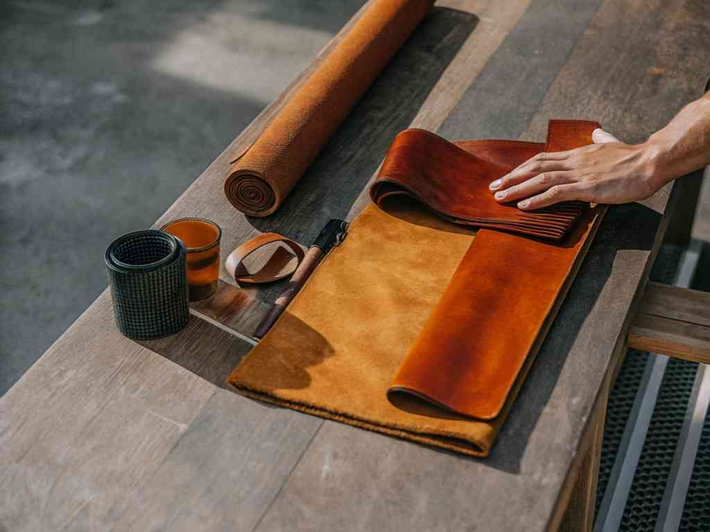 Hand selecting leather swatches on wooden table