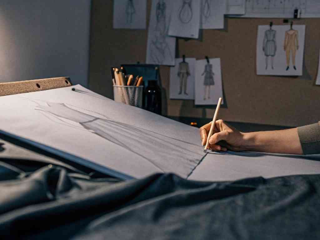 Designer drawing dress pattern on fabric in studio