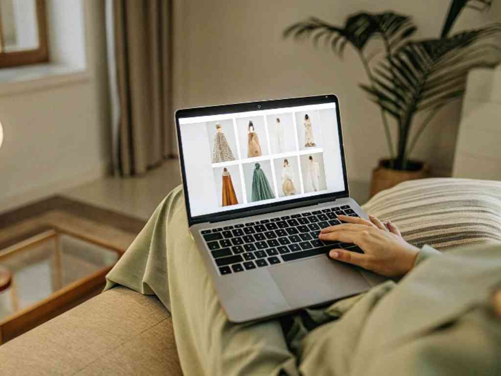 Person browsing dresses on laptop in cozy room