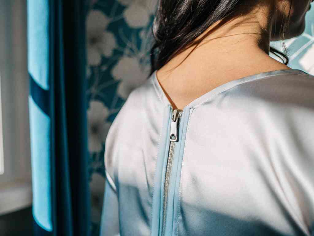Satin dress with silver zipper near window and blue curtain