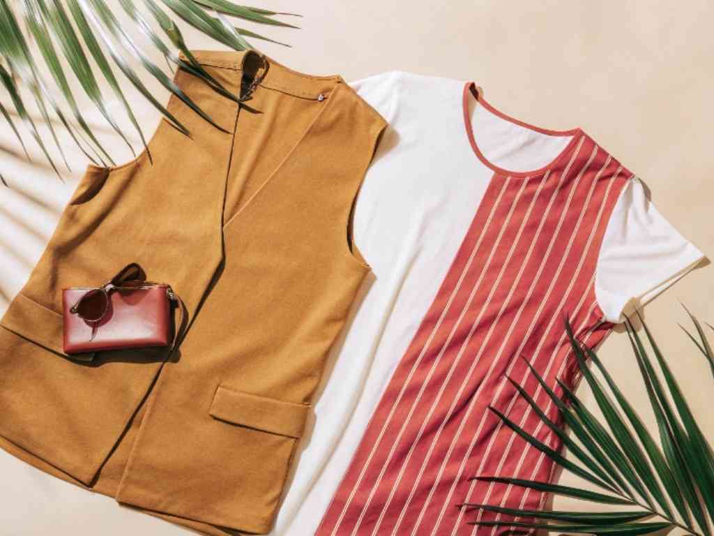A tan vest and a striped white t-shirt paired with a red handbag and sunglasses.