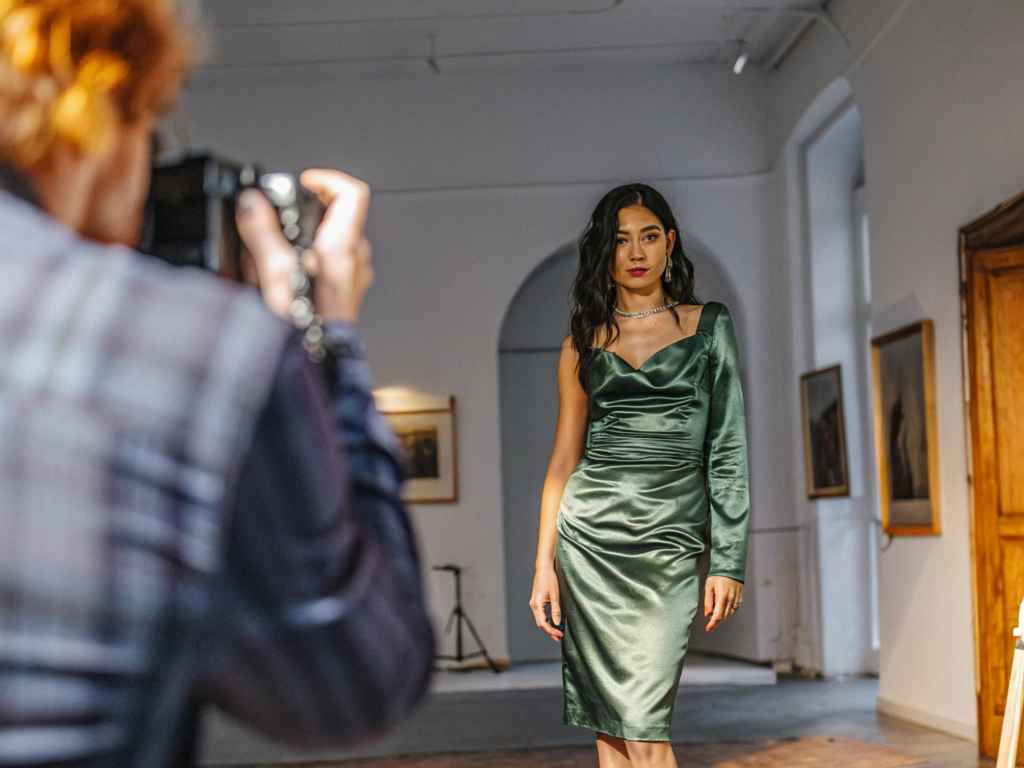 Woman in emerald green satin dress posing during photoshoot