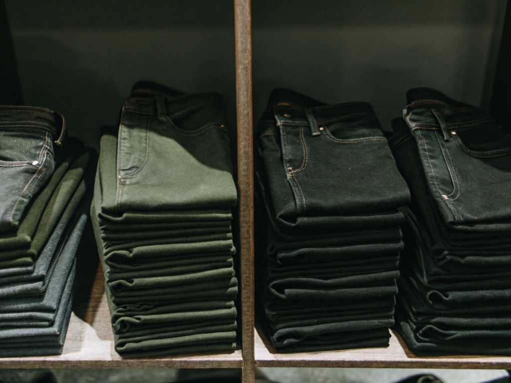Neatly folded dark jeans displayed on store shelves.