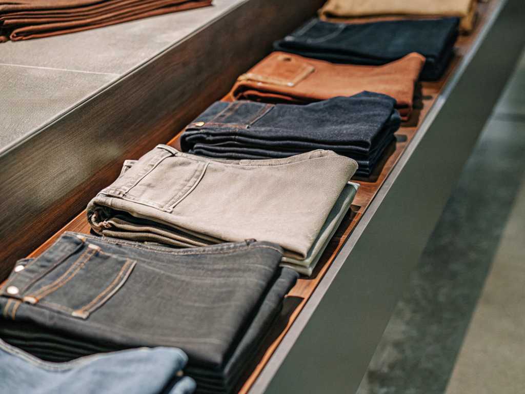 Variety of folded jeans arranged neatly on wooden store display.