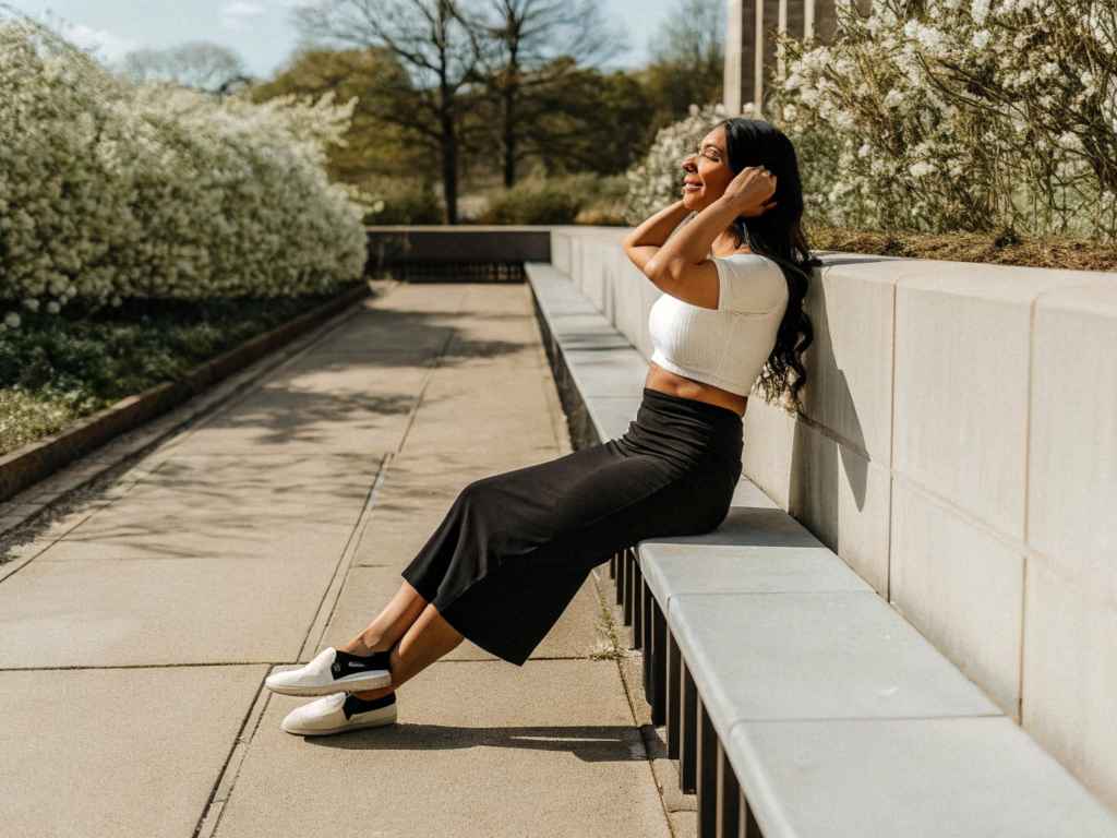Woman in crop top and black skirt smiling on garden bench