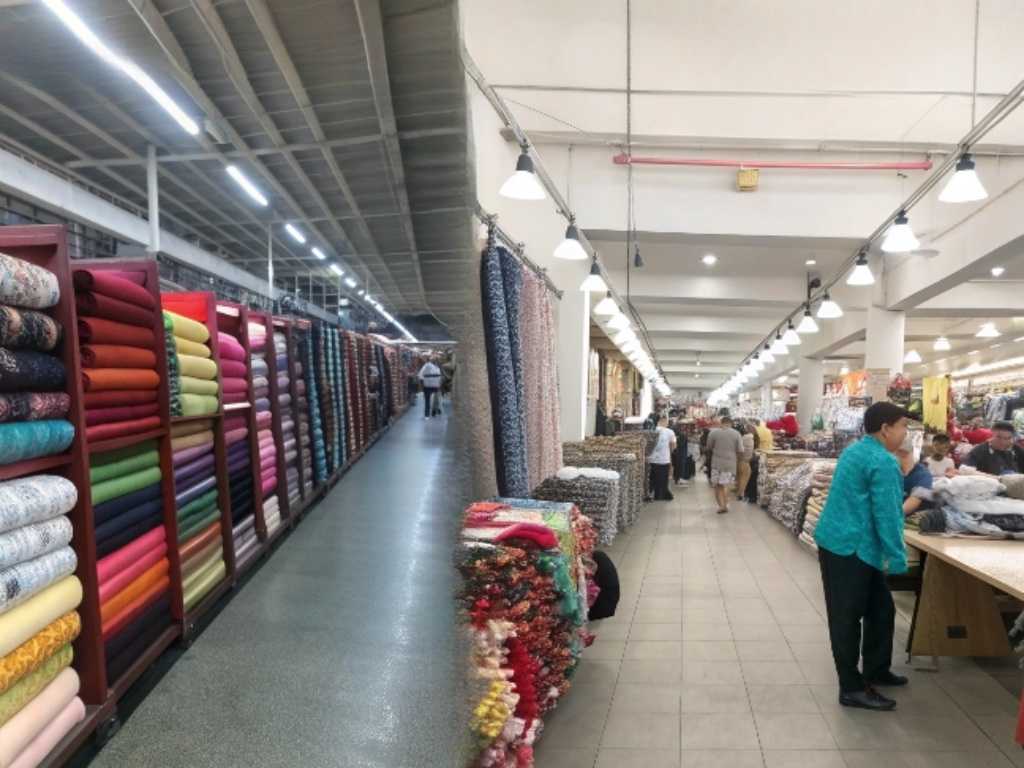 Large textile market with colorful fabric rolls and shoppers inside.