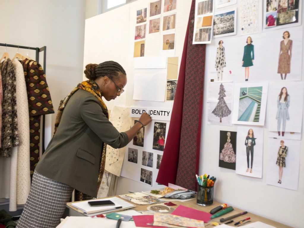 Fashion designer working on a mood board with fabric swatches and sketches.