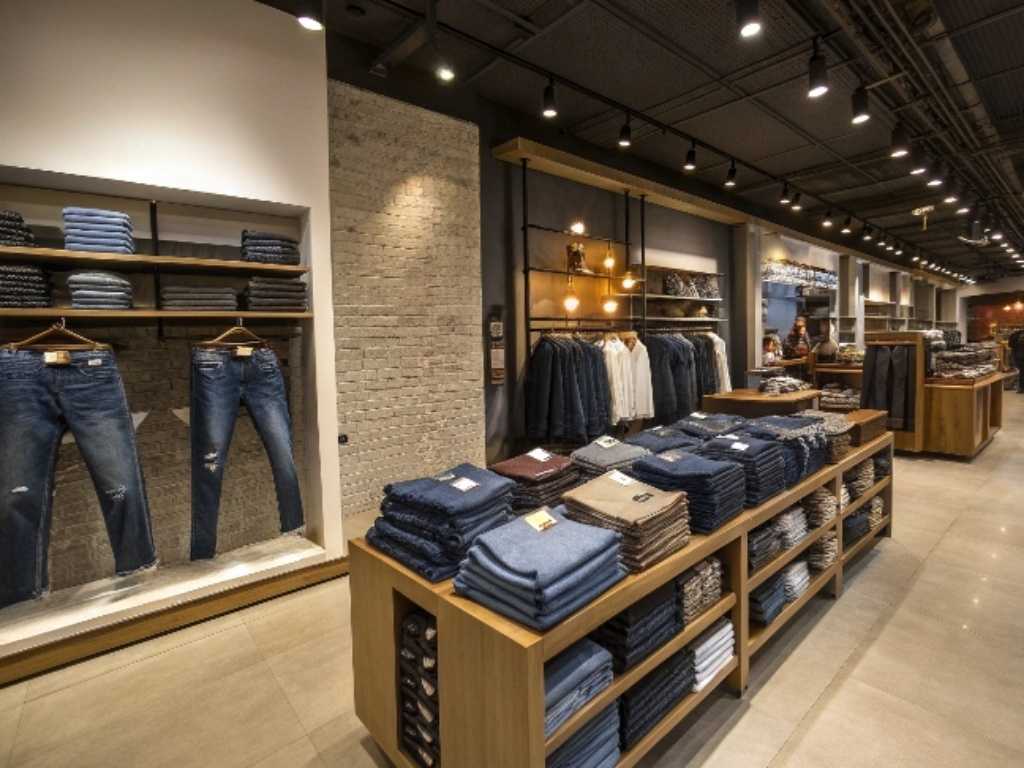 Modern retail clothing store with neatly folded jeans and shirts on display shelves.