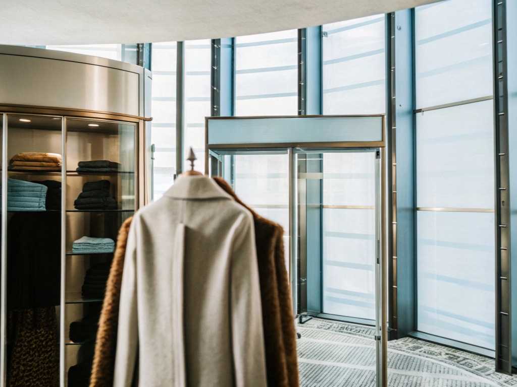 Elegant coats on mannequin in modern retail store interior.