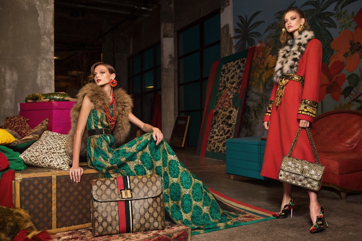 Two models in luxurious fashion with fur collars and statement accessories.