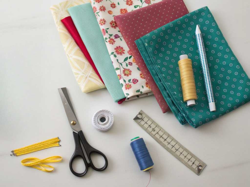 Sewing materials including colorful fabrics, threads, scissors, and ruler.