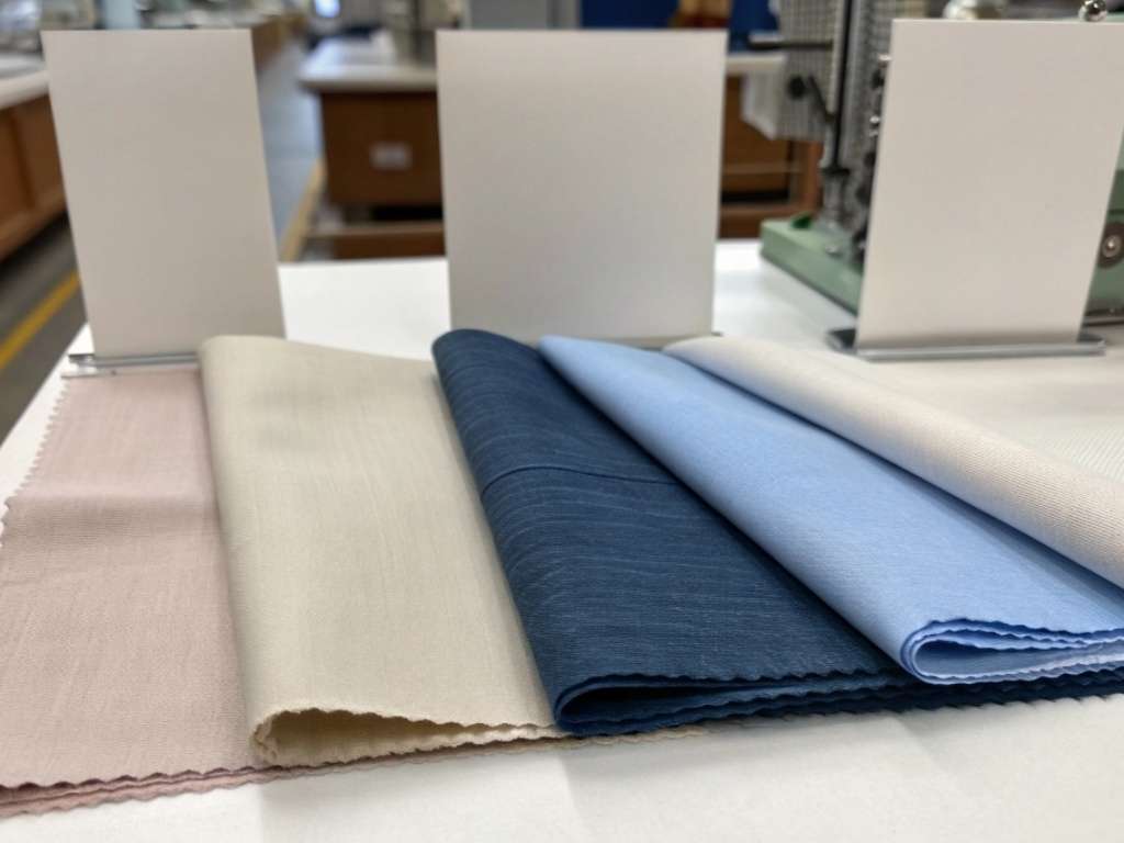 Folded fabric swatches in pastel and blue tones on display table.