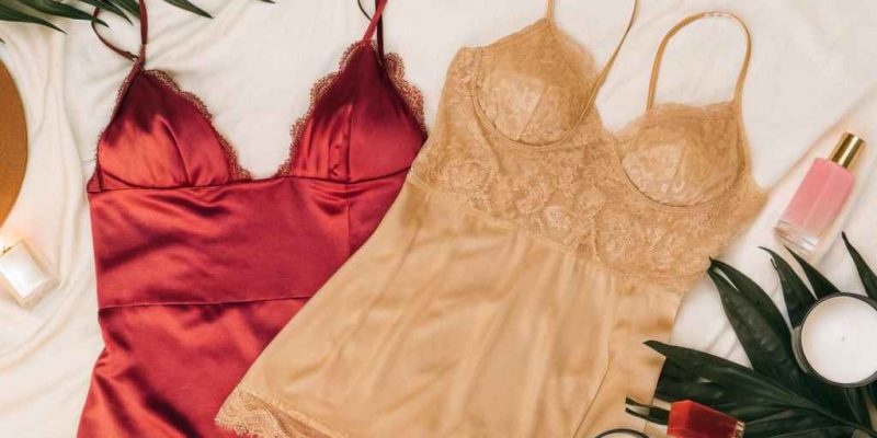 Satin and lace slip dresses in red and beige with candles and cosmetics